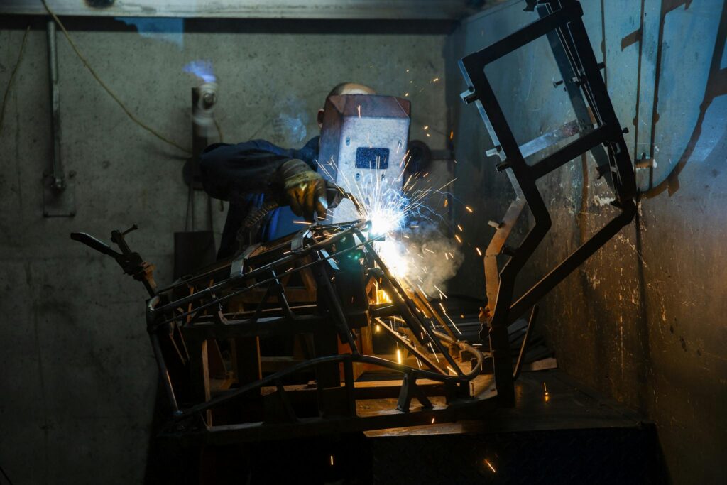 A welder working with sparks and smoke indoors, showcasing industrial skill and safety.